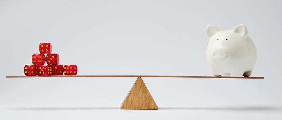 빨간 주사위 더미와 흰색 돼지 저금통이 나무 저울에 균형을 이루고 있는 모습